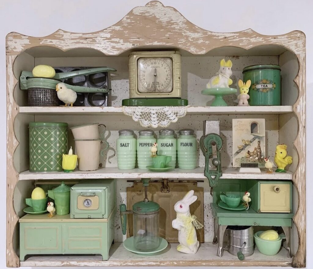 Shabby chic Easter hutch decor with mint green shelves, vintage canisters, chick and bunny figurines, pastel egg accents, and retro kitchen styling.