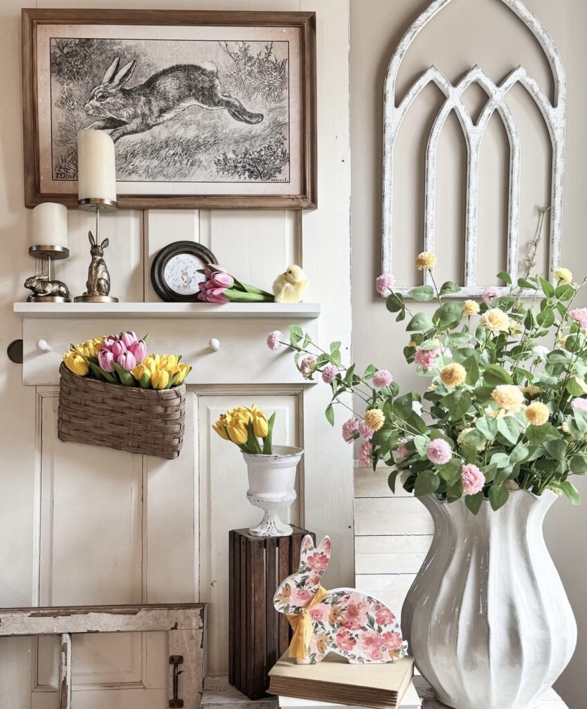 Cottage Easter table decor with tulips, a framed rabbit print, bronze bunny accents, a floral bunny cutout, and a large vase of pink and yellow flowers.