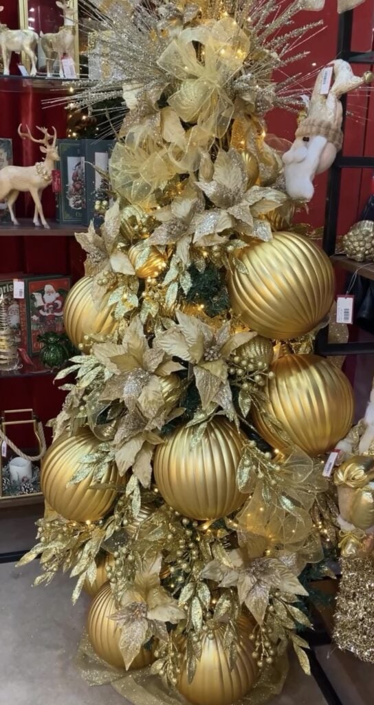 Gold-on-gold Christmas tree with oversized ornaments, oversized bow, and luxurious styling.