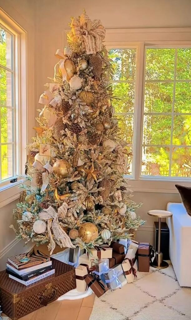 Designer gold Christmas tree in a cozy living room with elegant metallic ornaments and ribbon.