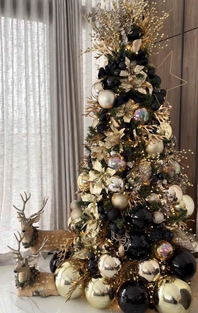 Gold Christmas tree decorated with woodland deer ornaments, warm lights, and gold star holiday decor.