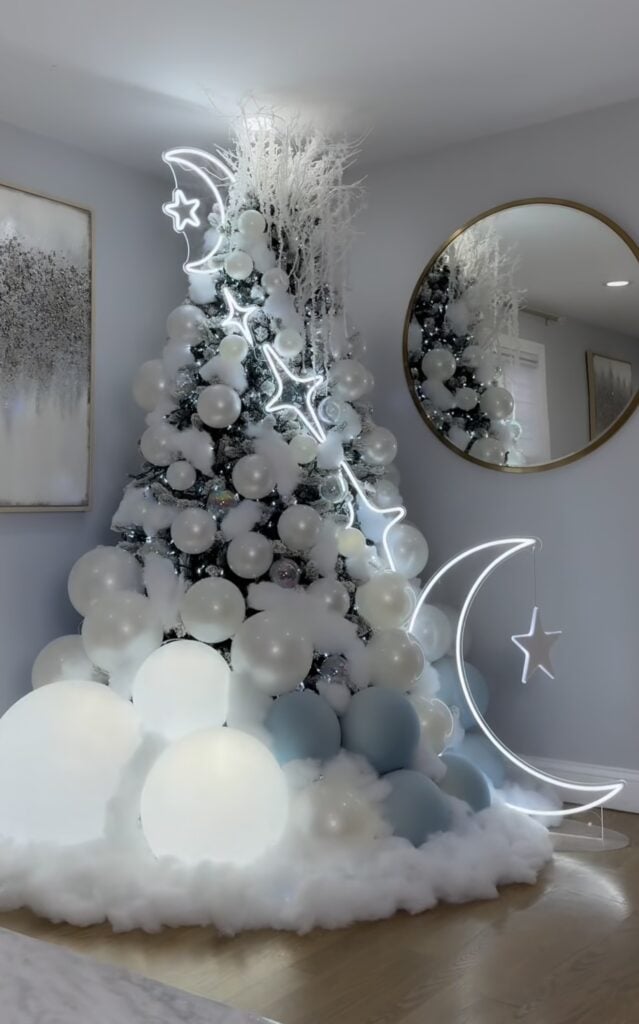 Modern Winter Solstice tree decorated with glowing moon and star lights, white ornaments, soft cloud accents, and celestial-inspired decor.