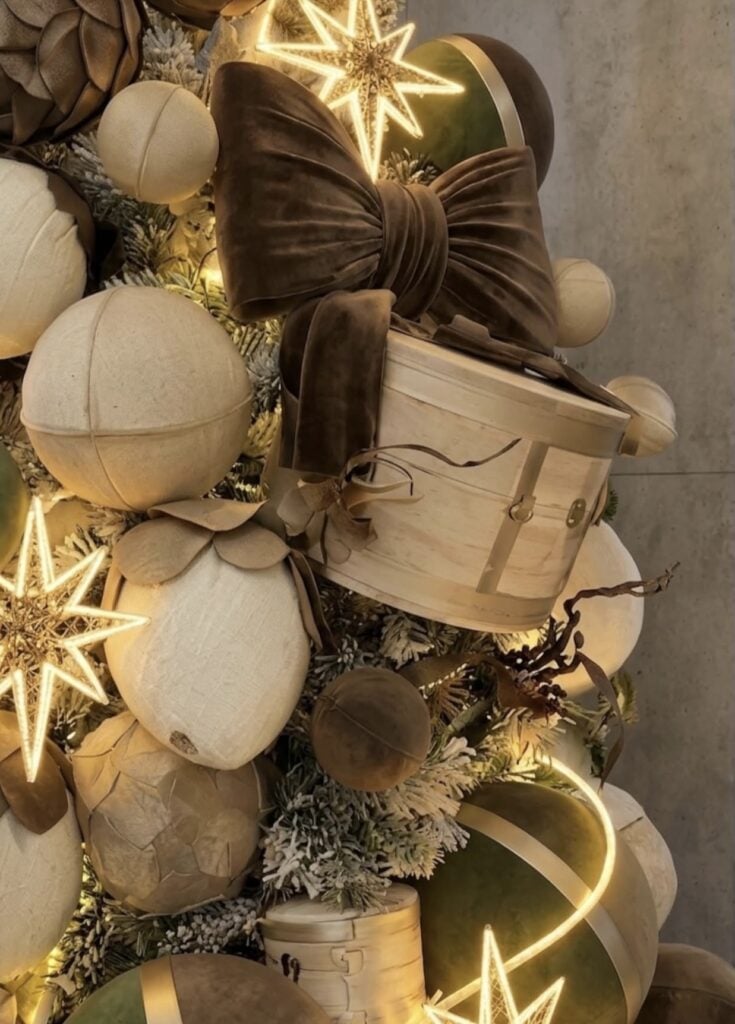 Close-up of a brown Christmas tree with layered ornaments, ribbons, and rich festive textures