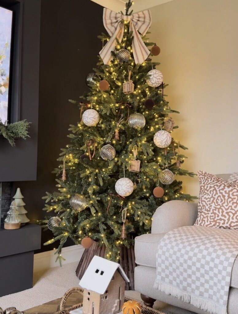 Brown Christmas tree topped with a large striped bow and layered neutral holiday decorations