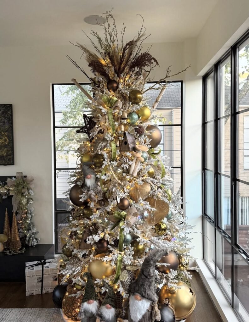 Woodland-inspired gold Christmas tree with natural greenery, ribbon, and rustic accents 