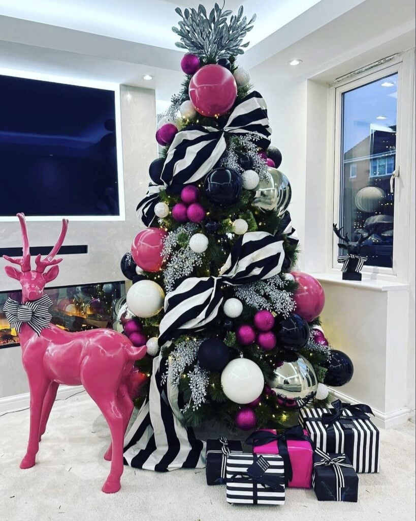 Black Christmas tree decorated with hot pink ornaments and bold pink accents for a playful, modern holiday look.