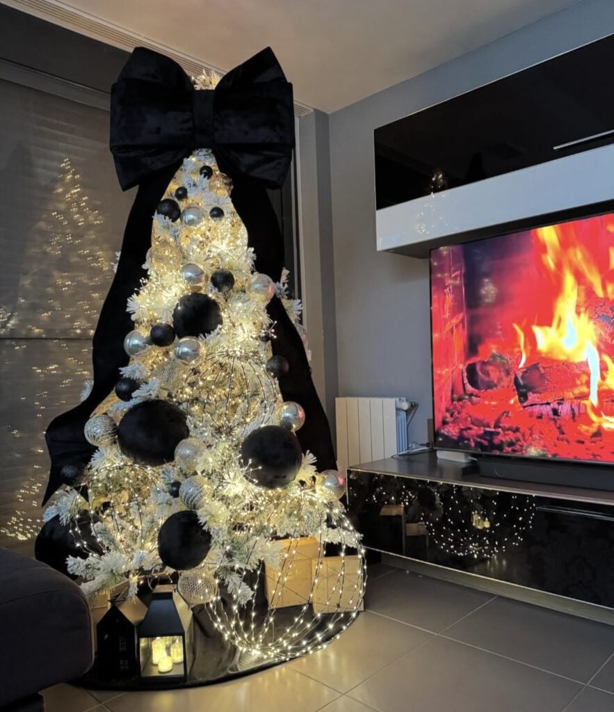 Black and white Christmas tree topped with an oversized statement bow and decorated with coordinating monochrome ornaments.