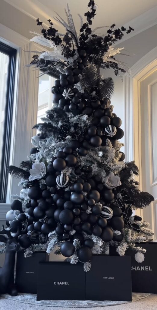 Black Christmas tree decorated with black and white ornaments, warm lights, and layered monochrome Christmas decorations.