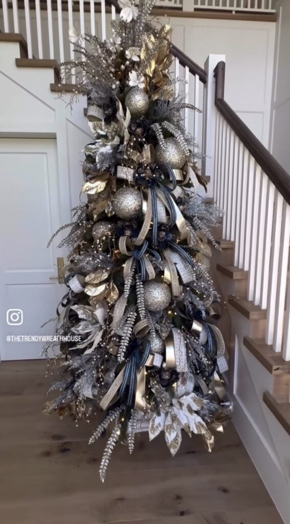Elegant Christmas tree decorated with blue and silver ornaments, metallic ribbon, sparkling picks, and warm white lights.