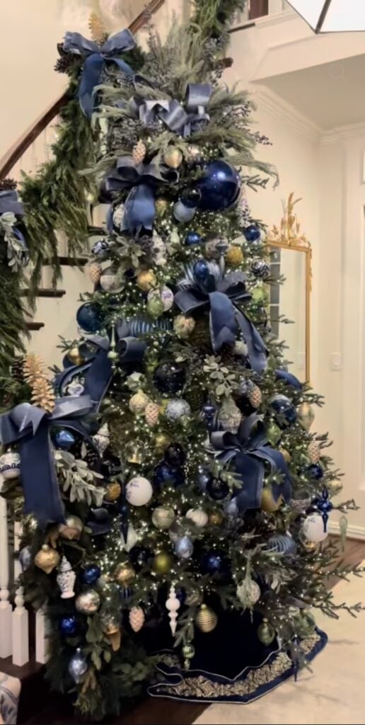 Christmas tree filled with blue ornaments, ribbon, decorative picks, and a mix of sparkling and textured finishes.