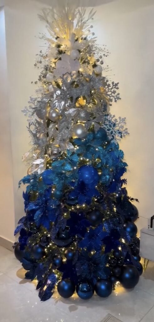 Ombré Christmas tree decorated with blue ornaments arranged from darker navy tones to pale icy blue shades.