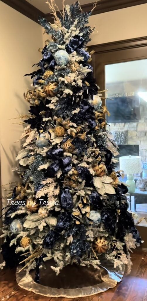 Layered blue Christmas tree decorated with navy, royal blue, and lighter blue ornaments in a mix of matte, shiny, and glittered finishes.