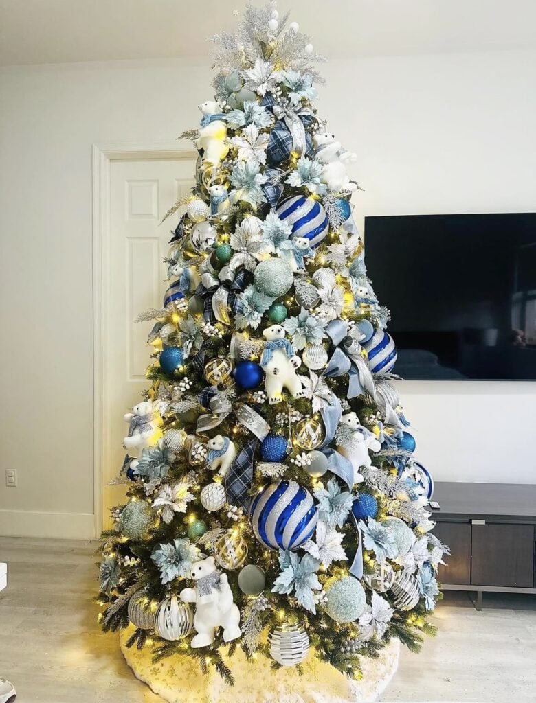 Blue Christmas tree layered with velvet ribbon, matte and glittered ornaments, textured picks, and metallic holiday accents.