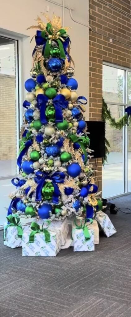 Bright blue Christmas tree paired with green ornaments, ribbon, greenery, and playful holiday accents.