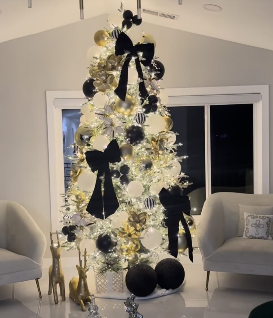 Christmas tree styled in black and white with black bows placed throughout the branches and coordinating ornaments.
