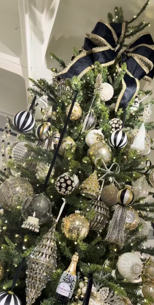 Glamorous Christmas tree styled like jewelry with black, white, and gold ornaments, metallic details, and sparkling accents.