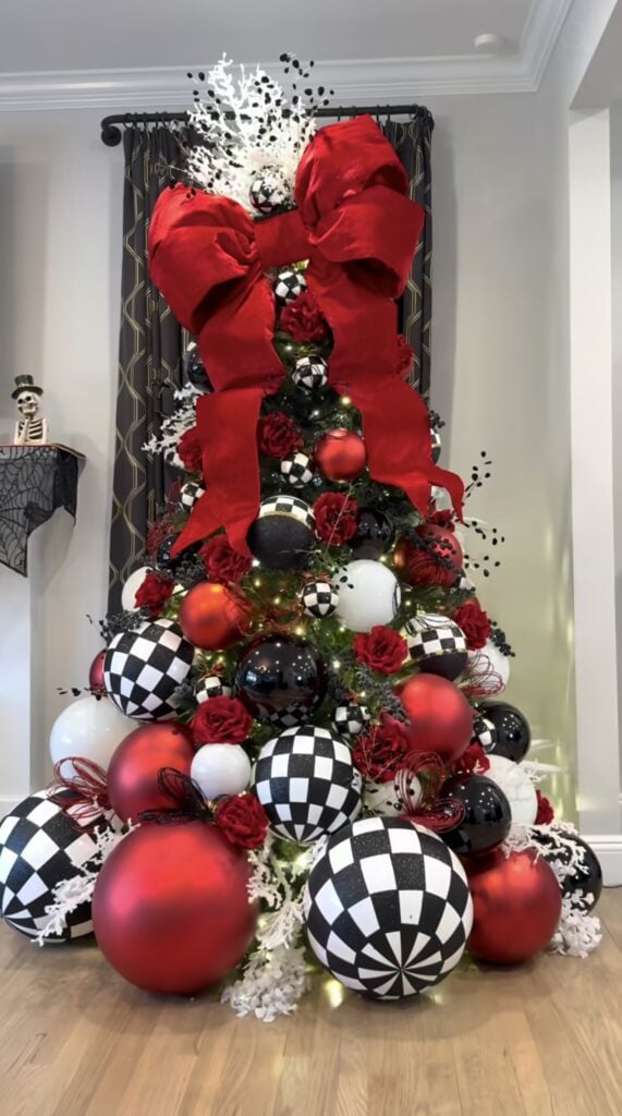 Christmas tree decorated in black and white with vivid red accents, ornaments, and ribbon for a bold holiday color combination.