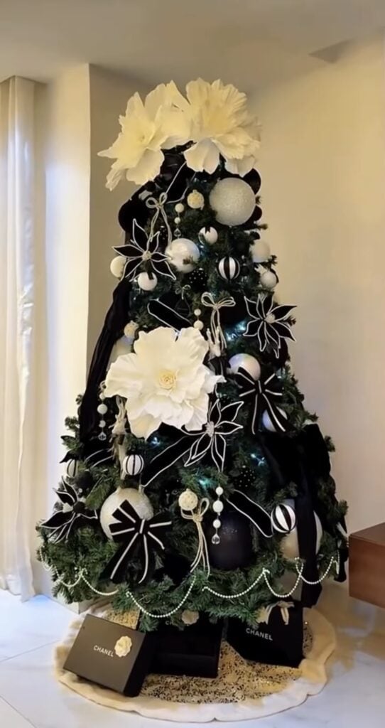 Christmas tree decorated with black and white poinsettias, matching ornaments, ribbon, and dramatic monochrome accents.