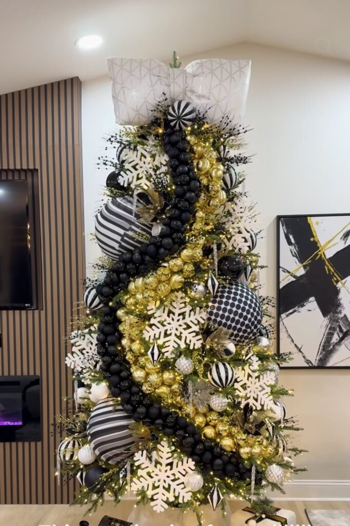 Christmas tree decorated in black and white with gold striped accents and coordinating metallic ornaments.