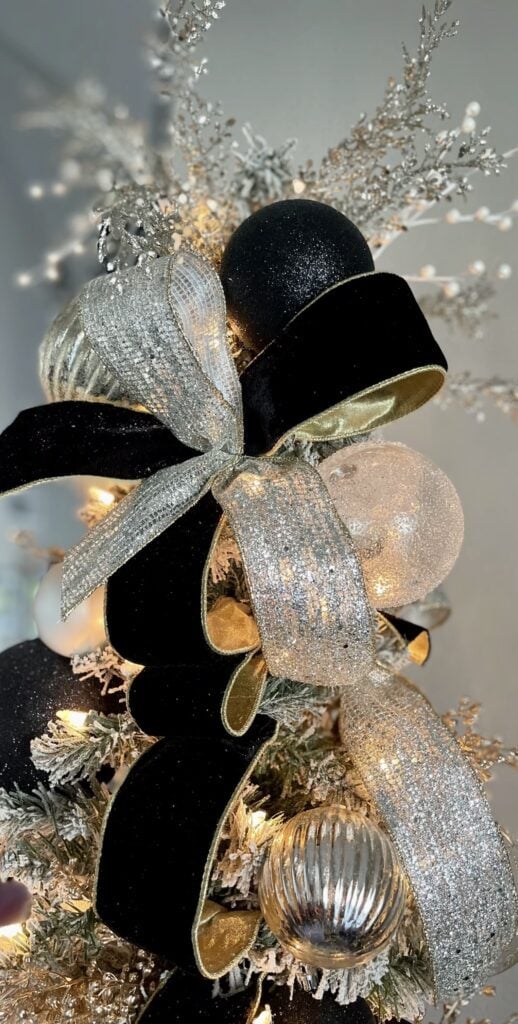 Close-up of a large black bow used as a dramatic decorative accent on a Christmas tree.