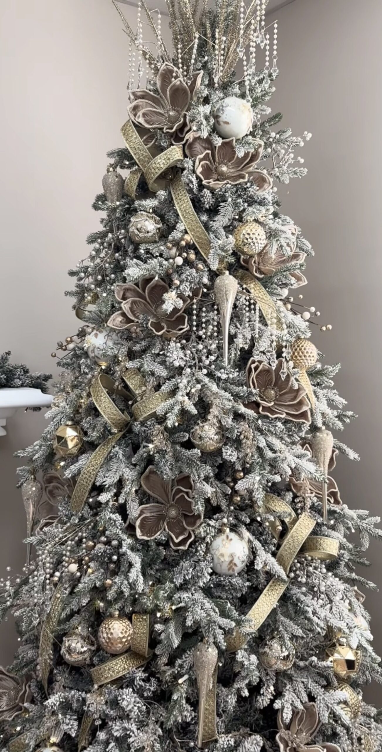 Christmas tree covered with flowers, greenery, ornaments, and botanical stems showing how florals can be layered through the branches.