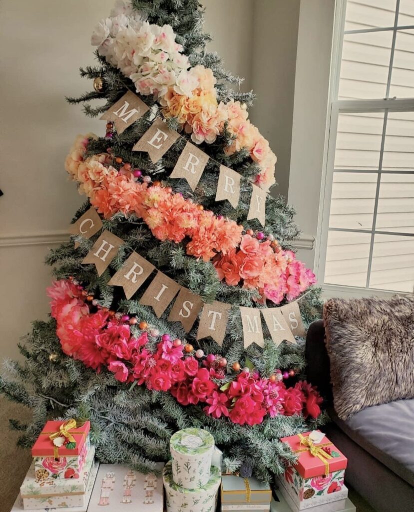 Floral Christmas tree featuring large blooms, greenery, ribbon, ornaments, and textured botanical accents throughout the tree.