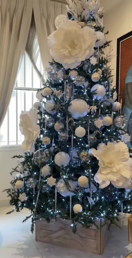 Christmas tree decorated with flowers, berries, leafy greenery, ornaments, and botanical stems for a full layered design.