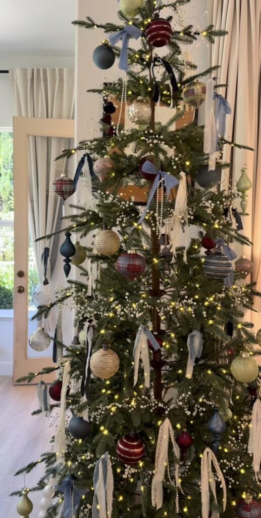 Vintage-inspired Christmas tree decorated with denim blue ornaments, nostalgic decorations, soft ribbon, and warm lights.