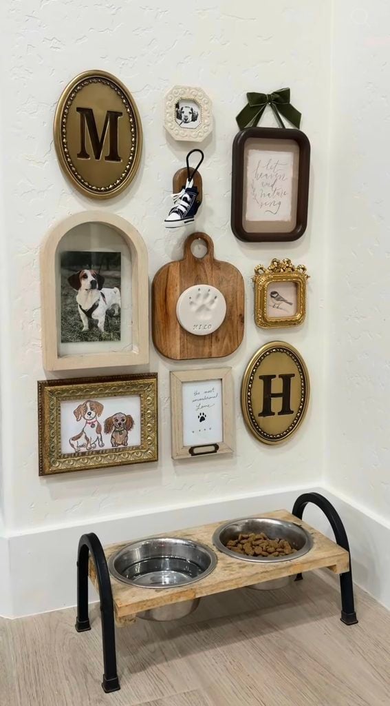 Whimsical dog gallery wall above raised food bowls with pet portrait, paw print, letters, framed dog illustration, tiny sneaker, and decorative frames.