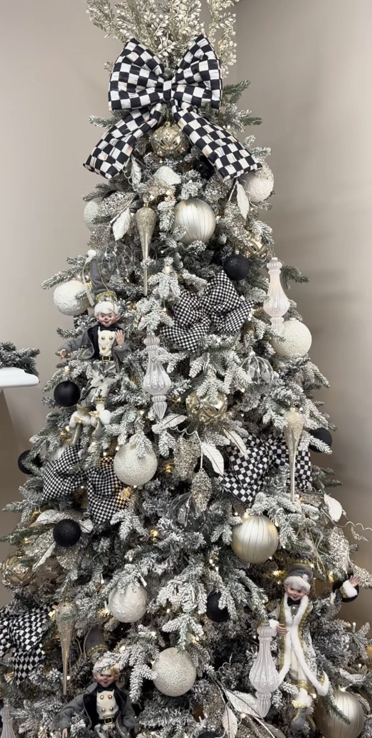 Flocked Christmas tree decorated with black and white ornaments for a crisp, snowy monochrome Christmas look.