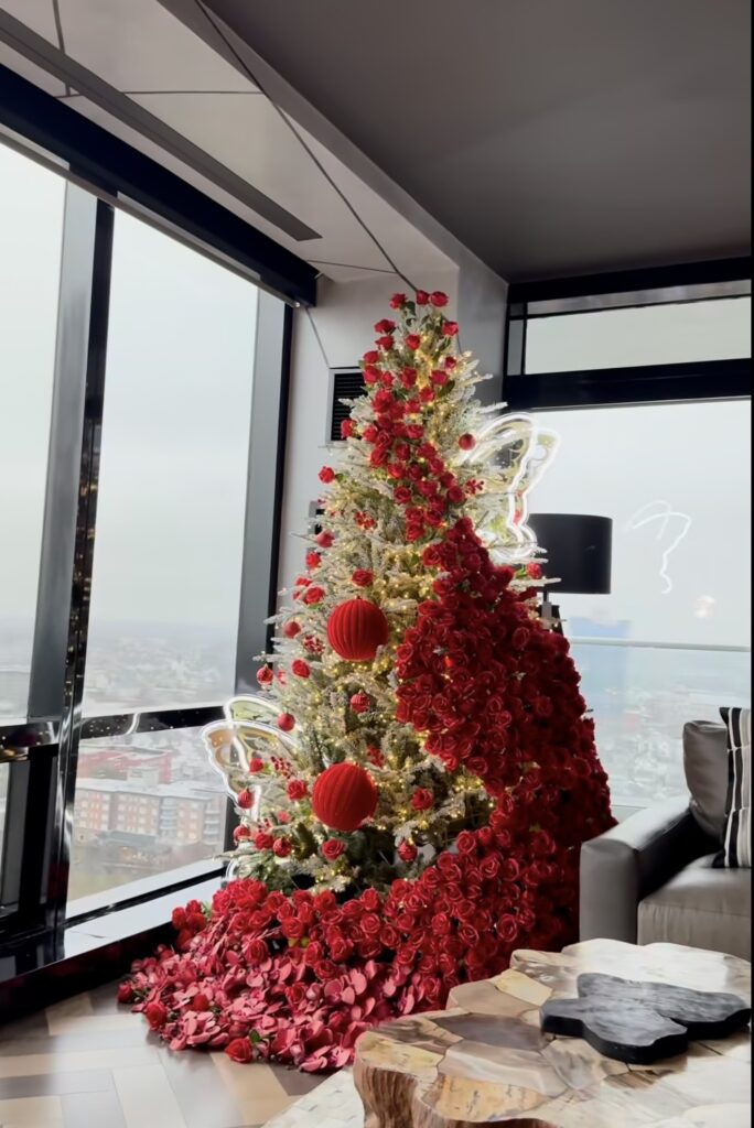 Floral Christmas tree decorated with abundant flowers, greenery, ornaments, and warm lights for a full holiday display.