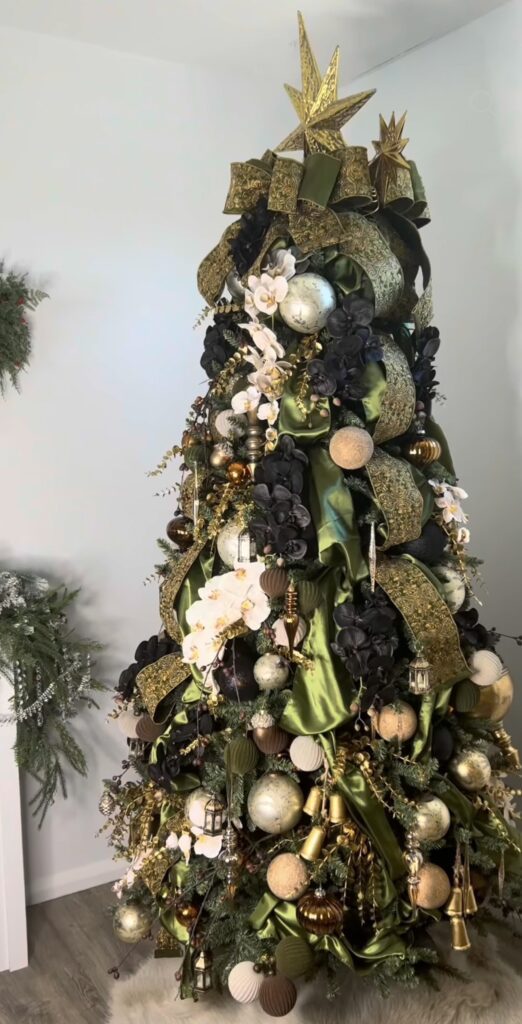 Christmas tree decorated with large magnolia flowers, greenery, ornaments, and layered botanical accents.