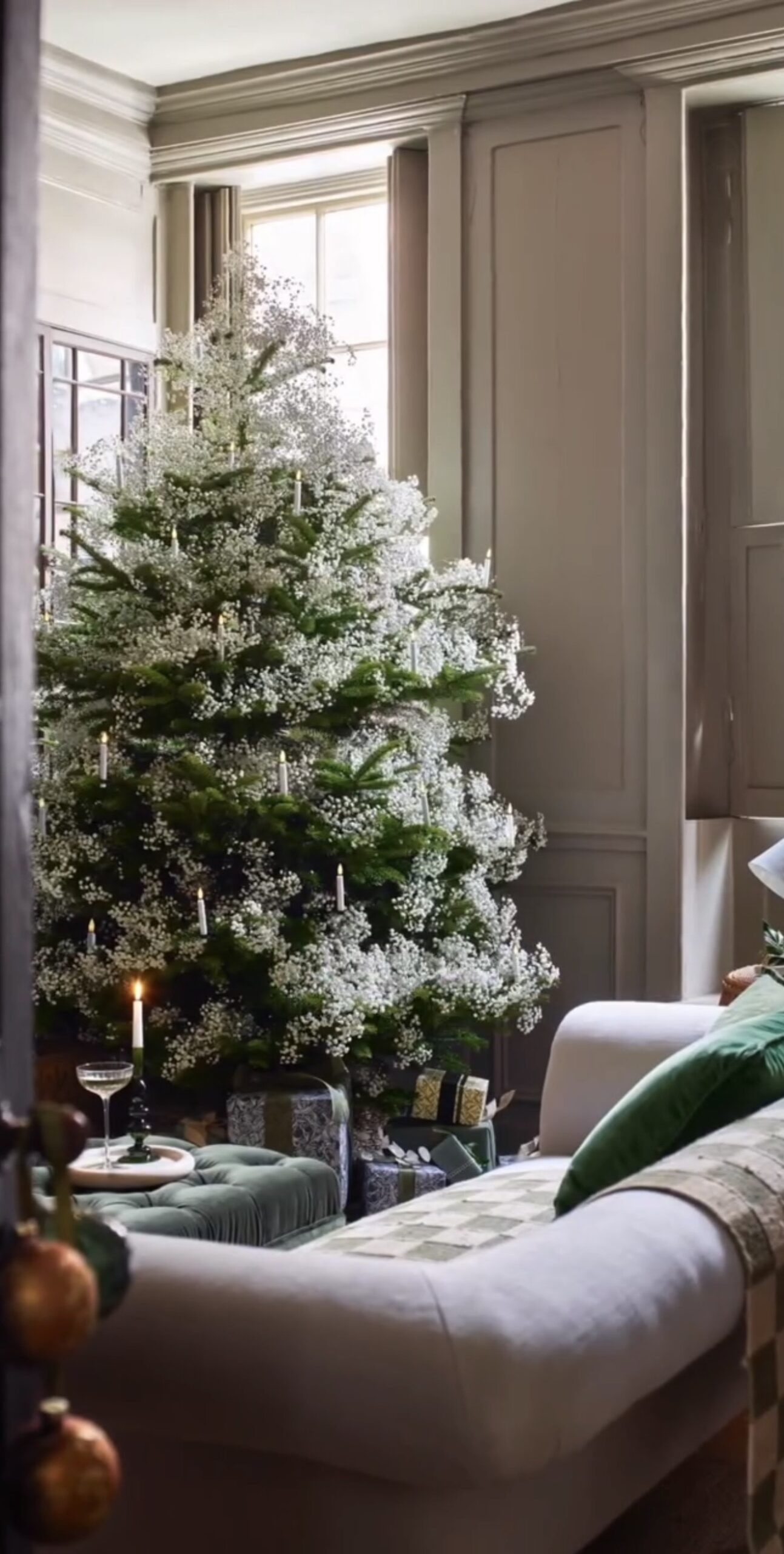Floral Christmas tree decorated with layered flowers, botanical greenery, ornaments, and warm holiday lights.