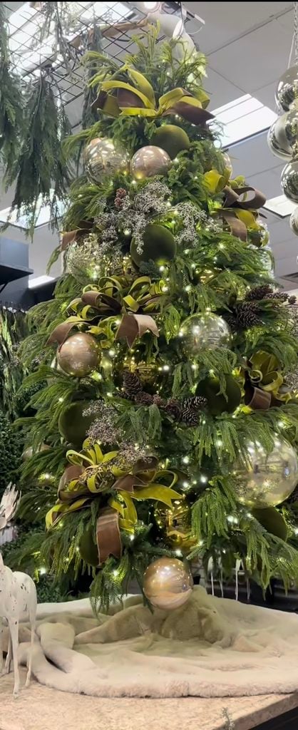 Green-on-green neutral Christmas tree decorated with layered green ribbon, tonal ornaments, greenery, and natural accents.