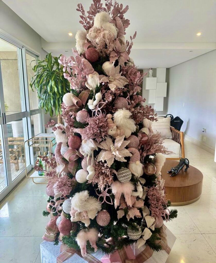 Christmas tree decorated with statement flowers, ornaments, greenery, and layered botanical details tucked among the branches.