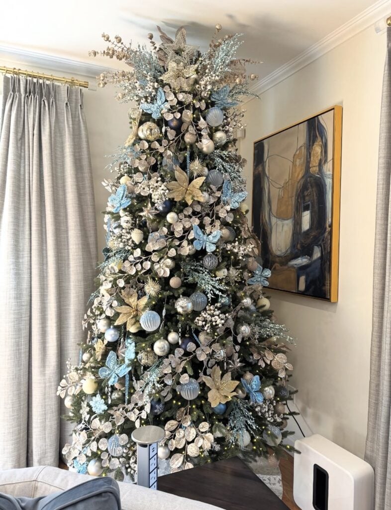 Light blue Christmas tree decorated with butterfly ornaments, pale blue ribbon, sparkling details, and delicate winter accents.