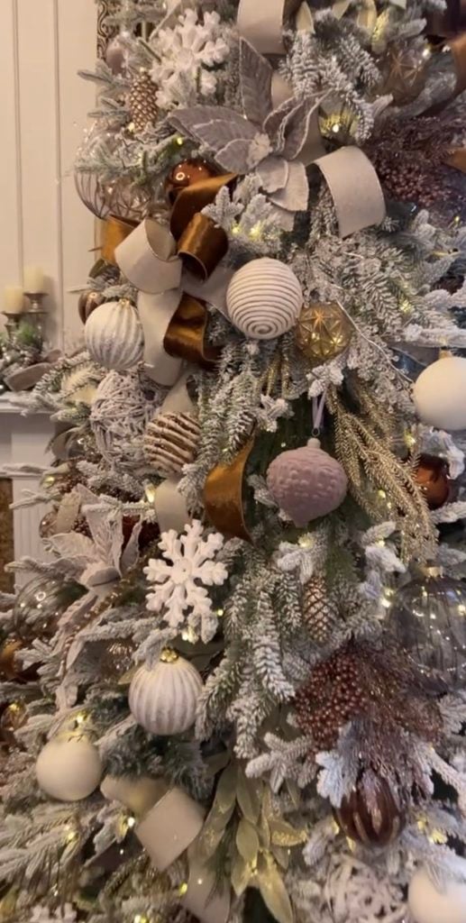 Pretty neutral Christmas tree decorated with warm cream, champagne, gold, and natural-toned holiday ornaments.