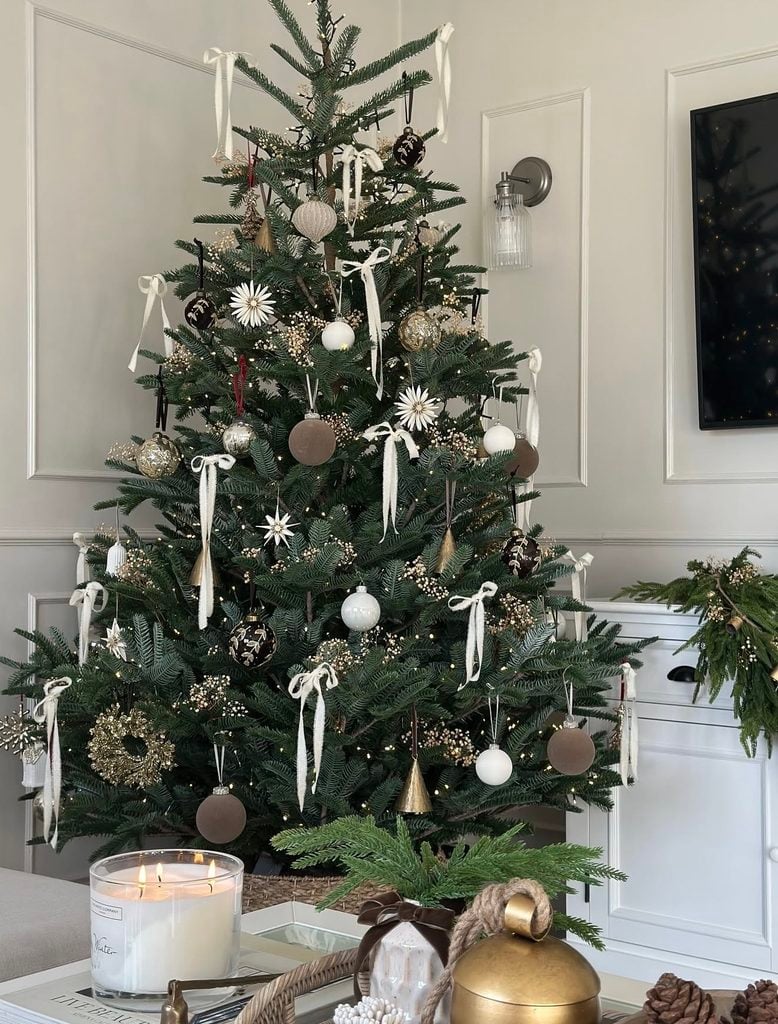 Simple minimalist neutral Christmas tree decorated with understated ornaments, natural textures, and warm white lights.