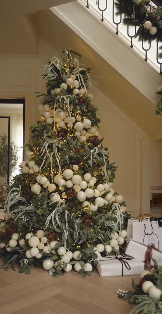 Styled neutral Christmas tree with layered cream, champagne, green, and natural decorations creating a rich holiday look.