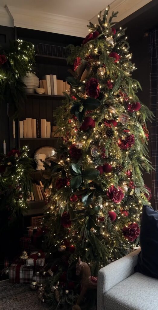Trendy floral Christmas tree decorated with oversized flowers, greenery, ornaments, and layered botanical details.