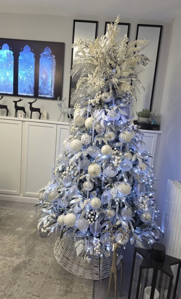 White Christmas tree illuminated with vivid blue lights and decorated with icy white ornaments for a bright winter wonderland effect.