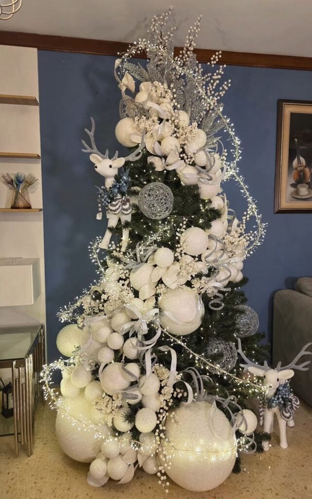 Whimsical white Christmas tree filled with playful ornaments, oversized decorations, feathery accents, sparkling details, and imaginative holiday styling.