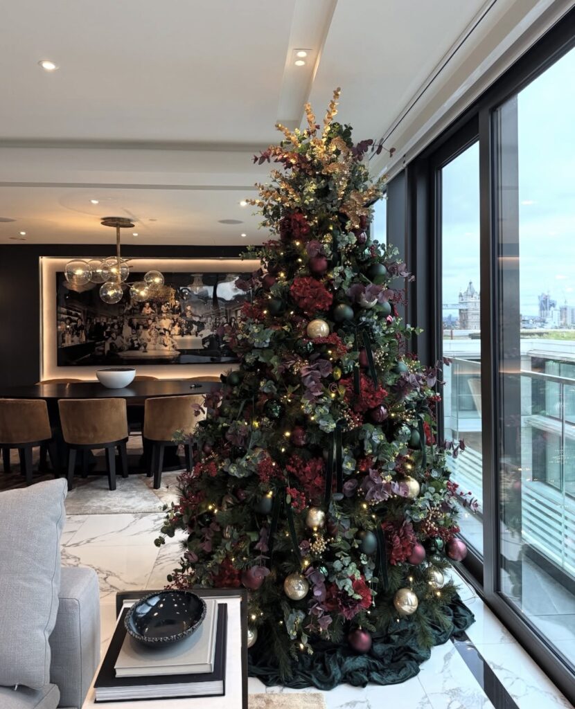 Burgundy floral Christmas tree filled with rich burgundy flowers, greenery, ornaments, and warm holiday lights.