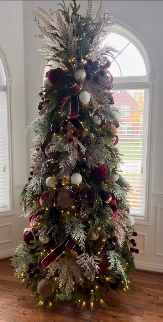 Burgundy Christmas tree decorated with deep red ornaments, berry sprays, velvet details and elegant seasonal accents.