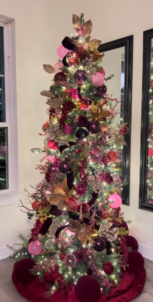 Styled burgundy Christmas tree with wine-colored ornaments, ribbon, berry picks and warm white Christmas lights.