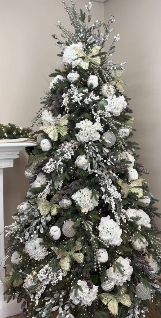 Christmas tree decorated with statement flowers, greenery, ornaments, and floral accents tucked throughout the branches.