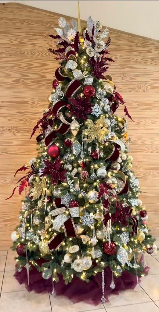 Luxurious burgundy Christmas tree layered with rich red ornaments, velvet details, berries and elegant holiday accents.