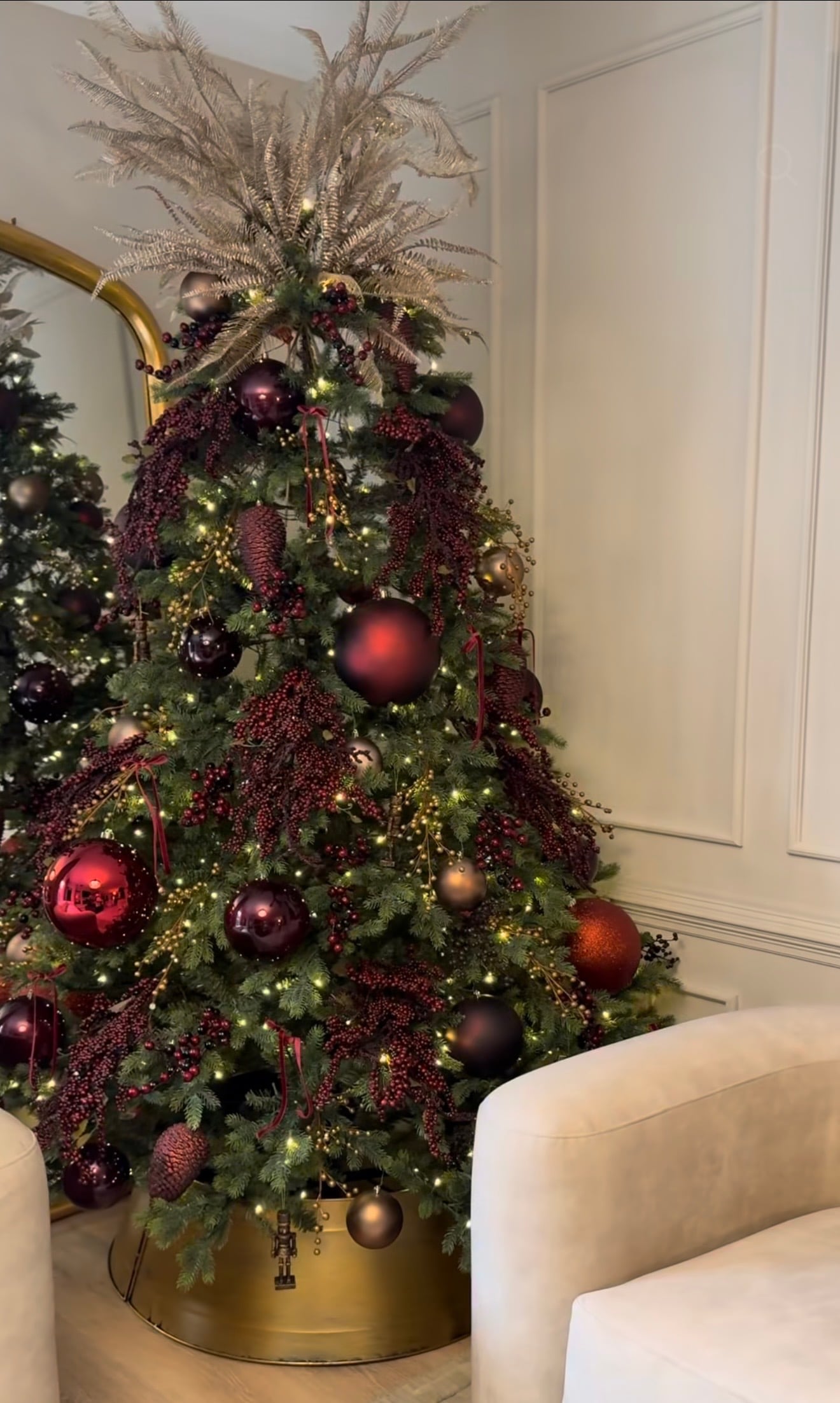 Luxe burgundy and gold Christmas tree decorated with wine ornaments, metallic gold accents and warm white lights.