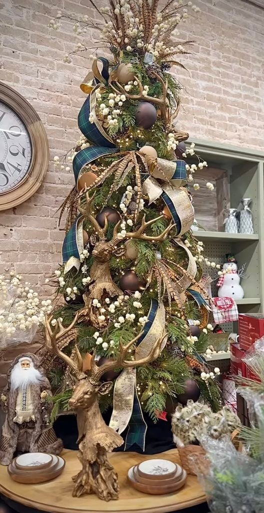 Statement neutral Christmas tree decorated with oversized ornaments, ribbon, champagne tones, and dramatic layered details.
