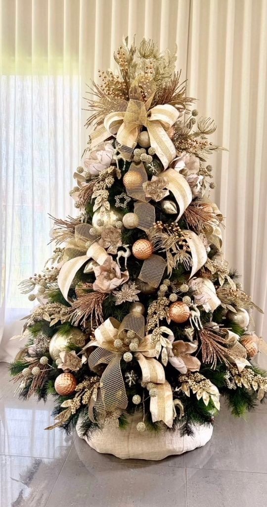 Neutral Christmas tree decorated with cream, champagne, brown, and green ornaments in a layered holiday design.